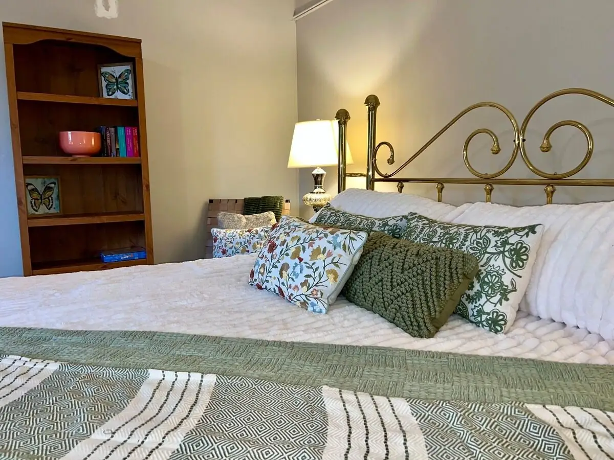 Brass bed made with fresh white linens and green accent pillows in a short-term rental after a Pure Heart turnover in Carrollton, GA