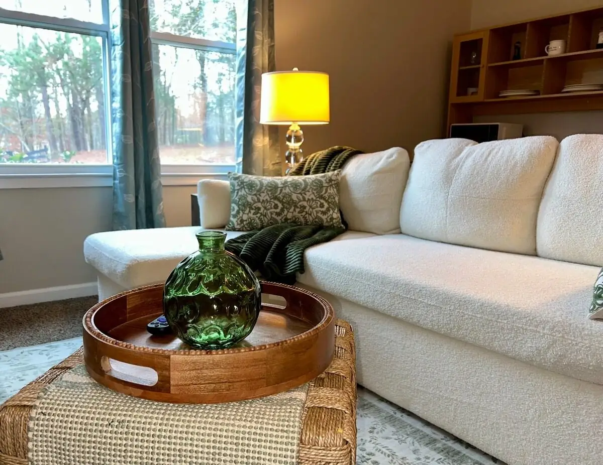Living area reset with a fluffed sectional, folded throw and styled tray before the next guest check-in in Carrollton, GA