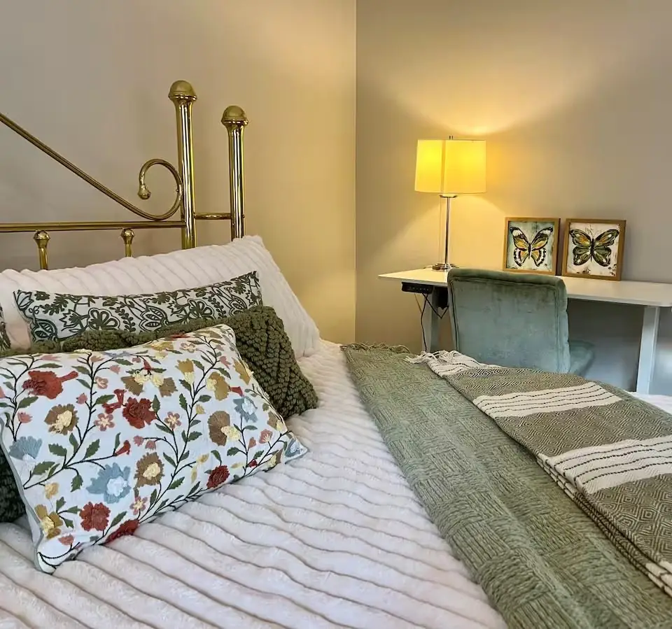 Close-up of a made bed with layered pillows and a fresh green blanket in a guest bedroom in Carrollton, GA