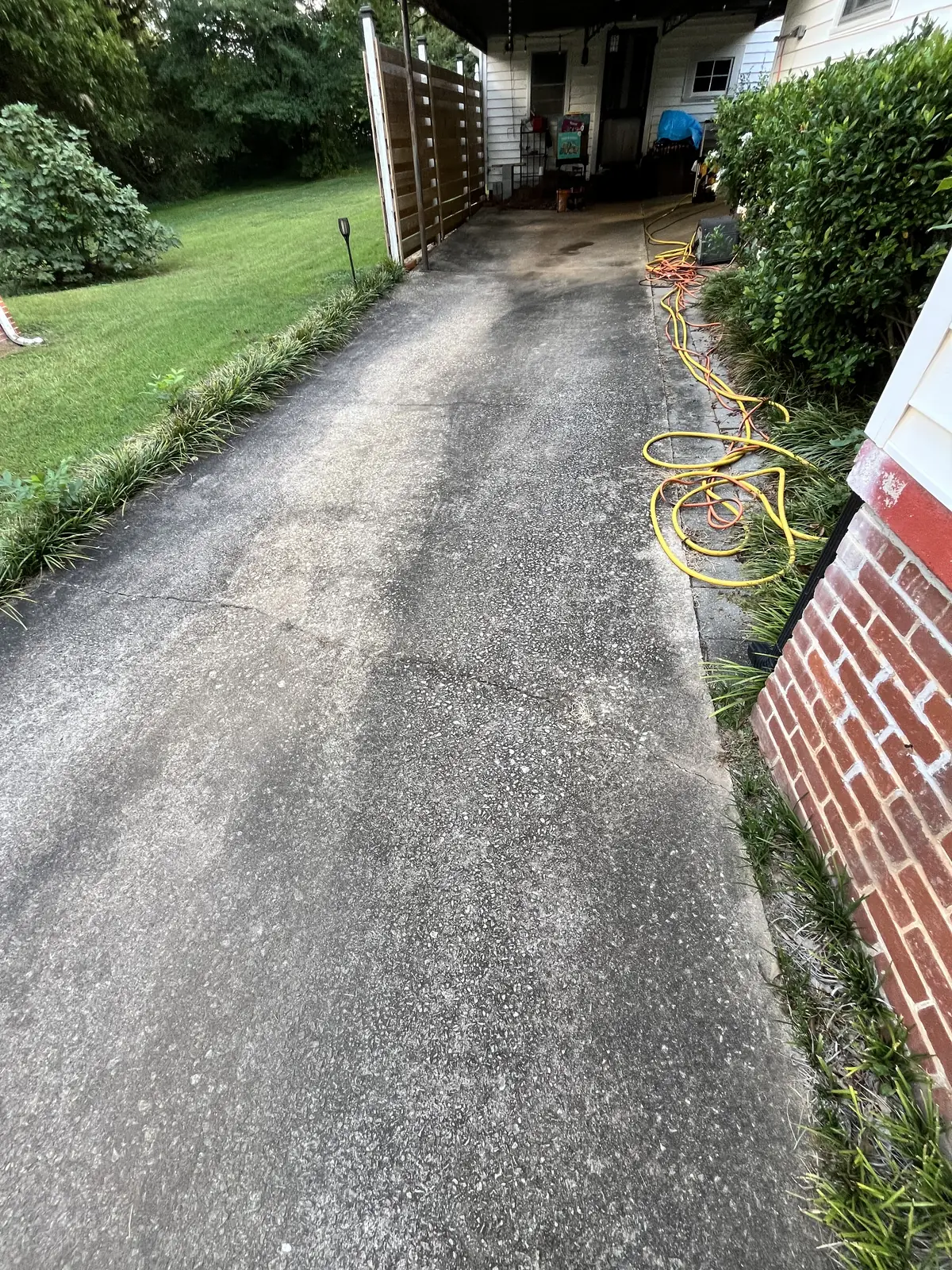 Driveway leading to a carport covered in dark buildup before pressure washing in Carrollton, GA